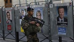 Voják francouzské armády prochází kolem plakát prezidentských kandidát.