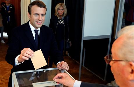 Favorit voleb Emmanuel Macron hlasuje. V pozadí stojí jeho manelka Brigitte...