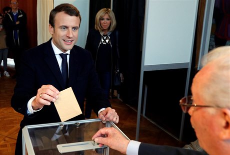 Favorit voleb Emmanuel Macron hlasuje. V pozadí stojí jeho manelka Brigitte...
