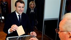 Favorit voleb Emmanuel Macron hlasuje. V pozadí stojí jeho manželka Brigitte...