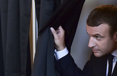 Francouzský prezident Emmanuel Macron vychází zpoza plenty se svým hlasovacím...