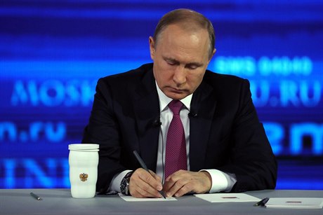 Prezident Vladimir Putin si píe poznámky, zatímco naslouchá otázce.