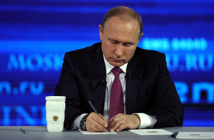 Prezident Vladimir Putin si píe poznámky, zatímco naslouchá otázce.