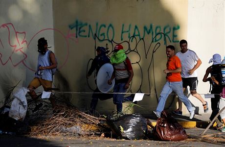 Demonstranti v Caracase utkaj okolo zdi s nasprejovanm npisem: jsem...