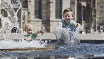 Chlapci osvěžující se vodou z kašny v centru Plzně.