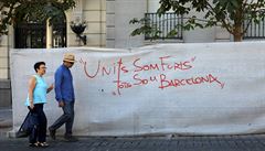 Pár prochází kolem graffiti nápisu v Madridu na kterém stojí: "Spolen jsme...