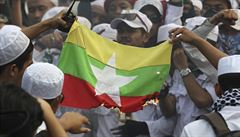 Protestující pálí vlajku Myanmaru.