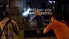 Demonstrant rozbijí okno nohou pi protestech v St. Louis.
