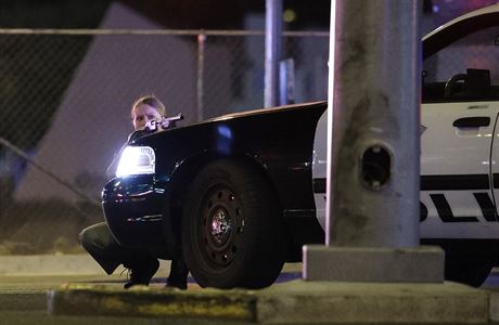 Policistka v Las Vegas se kryje za automobilem.