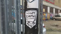 Sticker hlásající „Obsaďte Zemi“ zachycený na jednom ze sloupů v ulicích...
