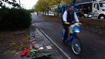 Lidé nechávají u cyklostezky květiny na památku obětí teroristického činu.