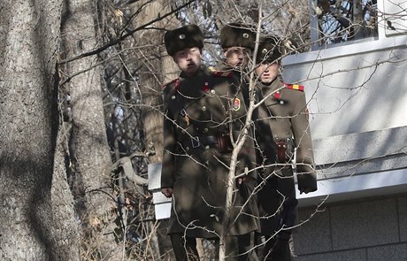 Trojice severokorejských voják v hraniním pásmu hledí smrem do Jiní Koreje.