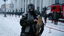 Demonstrant s plynovou maskou stojí před budovou parlamentu.
