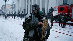 Demonstrant s plynovou maskou stojí ped budovou parlamentu.