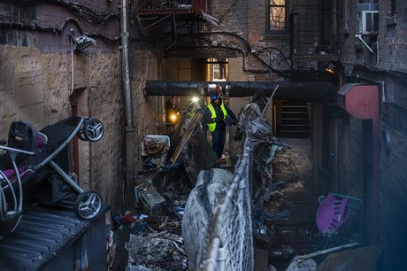 Policejní vyšetřovatelé procházejí trosky vyhořelého domu v newyorské čtvrti...