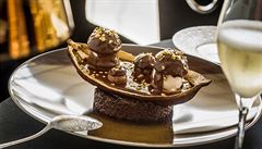 Profiterolky pln�né zmrzlinou s kakaovou drtí, podávané na krémovém l��ku z...