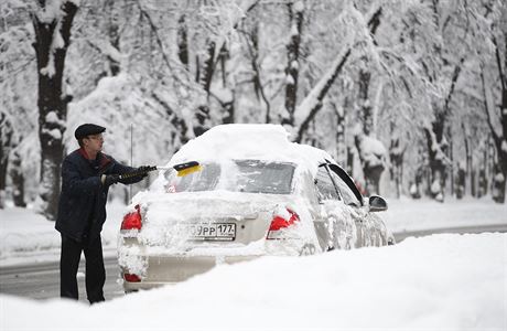 Mu odklízí sníh z auta po silném víkendovém snení, které zasáhlo ruskou...