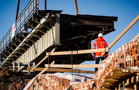 Dělník sleduje snášení ocelové konstrukce železničního mostu přes ulici Prvního...