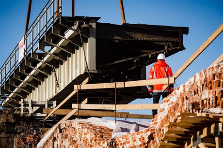 Dělník sleduje snášení ocelové konstrukce železničního mostu přes ulici Prvního...