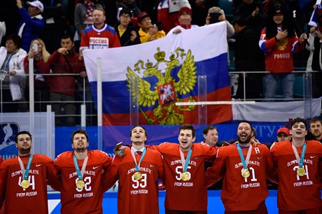 Ruští hokejisté zpívají národní hymnu ze zlatými medailemi na krku. Za nimi...