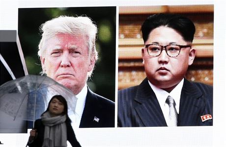 ena prochz ped ob obrazovkou s fotografiemi Kim ong-una a Donalda Trumpa.