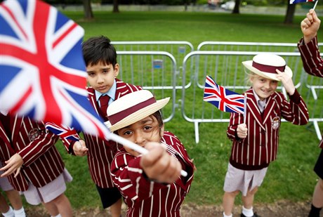 Před hradem Windsor mávají děti v uniformách vlaječkami. Přípravy na svatbu...