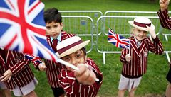 Před hradem Windsor mávají děti v uniformách vlaječkami. Přípravy na svatbu...