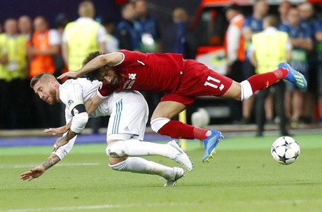 Liverpoolský stelec Mohamed Salah padá po zákroku obránce Realu Sergia Ramose.