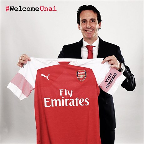 Nový trenér Arsenalu Unai Emery drí v ruce dres týmu. Na rukávu má dres logo...