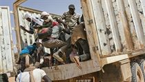 Migranti lezou na korbu náklaďáku v nigerském městě Assamaka. Zkouší překročit...