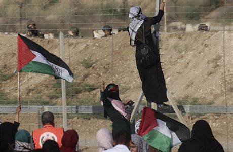 Jedna z palestinskch demonstrantek povsila svoji vlajku na hranin plot.