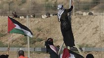 Jedna z palestinských demonstrantek pověsila svoji vlajku na hraniční plot.