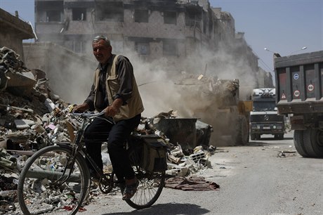 Buldozer likviduje trosky domů v Sýrii.