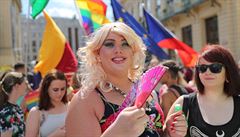 Úastnice pochodu Prague Pride v pozadí s duhovými LGBT vlajkami.