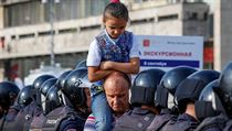 Mu nese na ramenou holiku okolo policejn blokdy bhem protest v Rusku,...