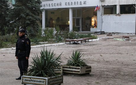 Ruský policista stojí u vchodu do koly.