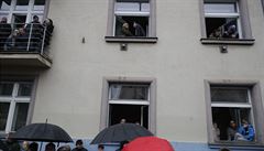 Lidé sledují vojenskou pehlídku i z oken okolních dom.