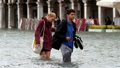 Pár se brodí vodou v centru Benátek.