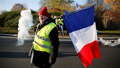 Demonstrant s francouzskou vlajkou blokující silnici.