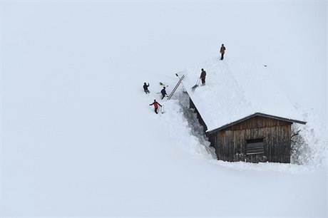 Lidé se snaí odstranit sníh ze stechy, aby se nepropadla.