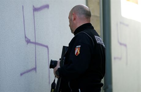 Policista zkoumá nasprejovaný hákový kí.