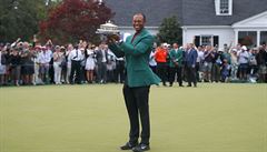 Tiger Woods se zeleným sakem a trofejí pro vítze.