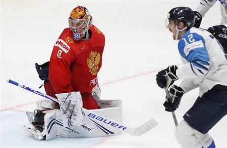 Ruský branká Andrej Vasilevskij okovan hledí za sebe, zatímco stelec gólu...