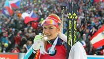 Gabriela Koukalová se zlatou medailí, za ní slavící čeští fandové.