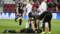 Na zemi leí Michael Ngadeu ze Slavie, nad ním se sklání Milan koda a Simon...