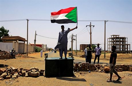 Súdánský demonstrující drí vlajku své zem zatímco stojí na barikádách v...