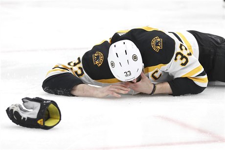 Bostonský kapitán Zdeno Chára leí otesený na led po zásahu pukem do oblieje...