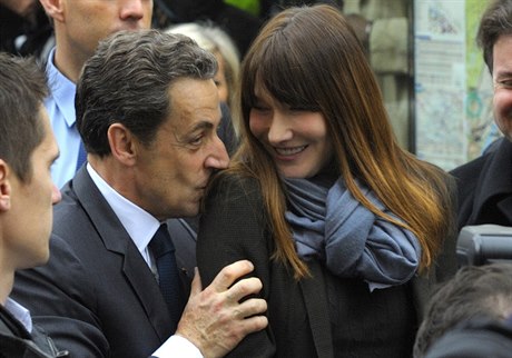 Nicolas Sarkozy líbá na rameno manelku Carlu Bruniovou.