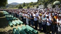 Lidé se modlí u rakví nově identifikovaných obětí ze masakru ve Srebrenici z...