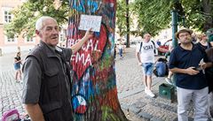 Muž prodává fixy na malování po Lennonově zdi.